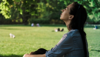 אישה שנמצאת בטבע ולקוחת נשימה עמוקה, דבר שחשוב מאוד לבריאות הכללית של הגוף