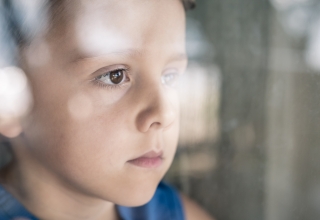 ילד על הספקטרום האוטיסטי עומד ליד חלון ומסתכל החוצה