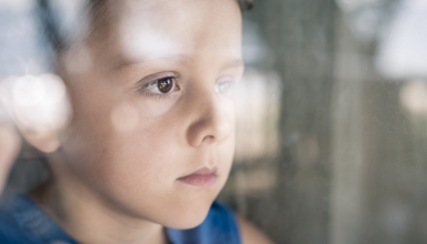 ילד על הספקטרום האוטיסטי עומד ליד חלון ומסתכל החוצה