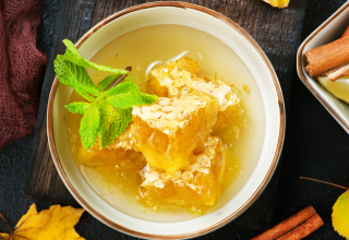 קערה עם חלת דבש שמחזק את המערכת החסיונית, ומסביב מקלות קינמון, ליים וכובי אניס