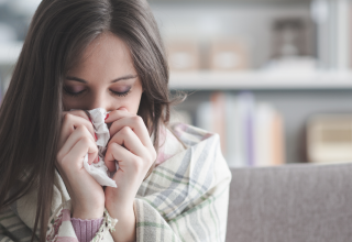 אישה שמקנחת את האף וסובלת משפעת שייתכן ויותר מסוכנת השנה